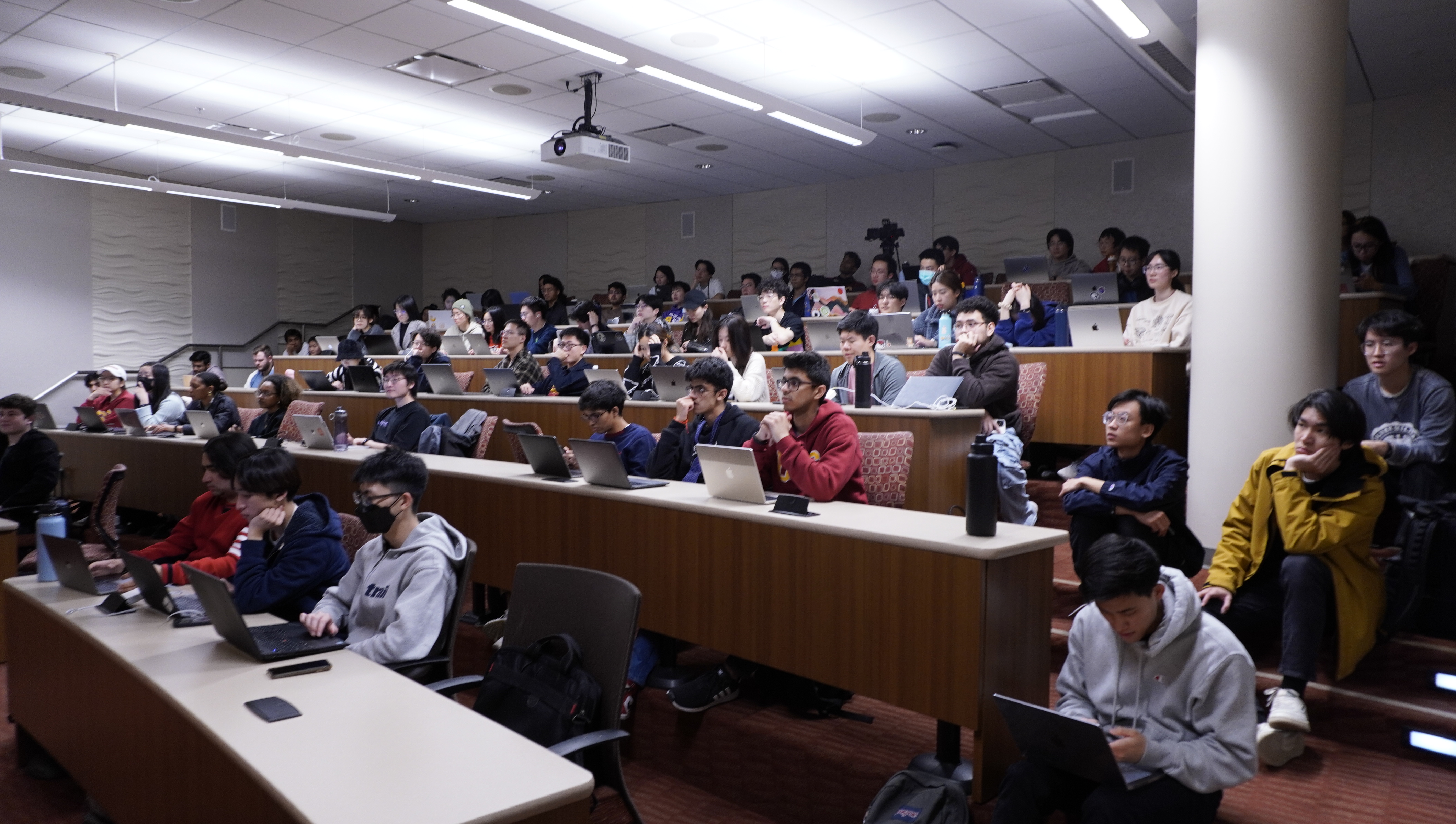 Workshop room at capacity, with hackers sitting on the steps.